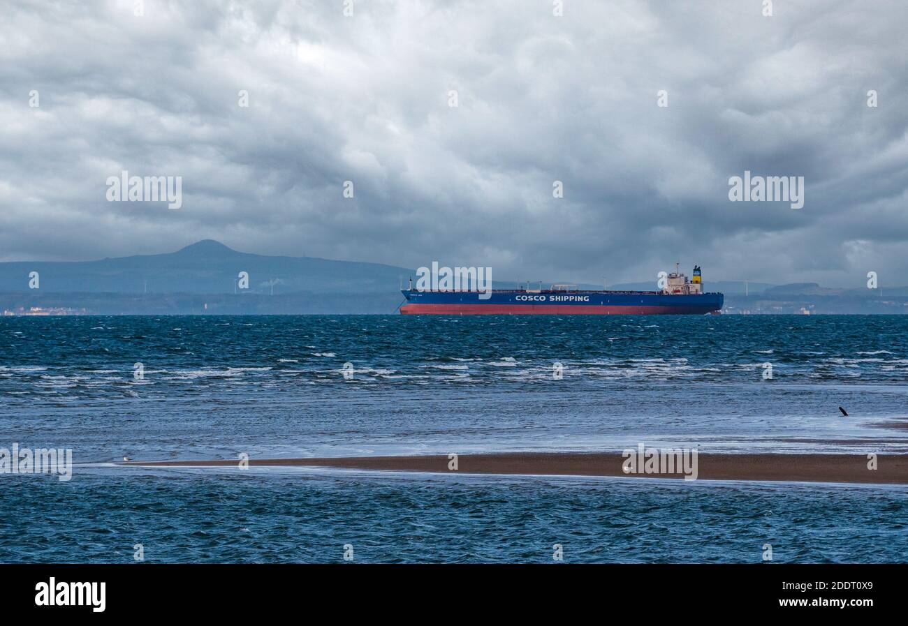 Cosco Shipping freight ship anchored in Firth of Forth on a windy cloudy day with a view of Fife, Scotland, UK Stock Photo