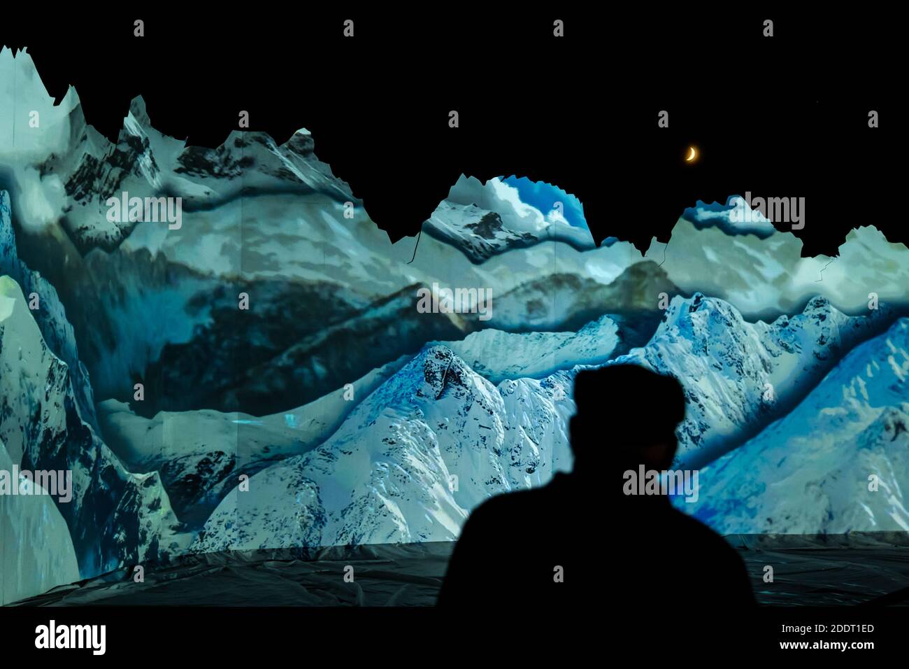 Silhouette of man watching Winter mountain landscape projection with crescent moon, Edinburgh Zoo, Scotland, UK Stock Photo