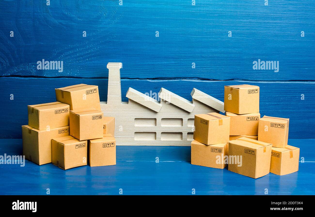 A figurine of a plant and a lot of boxes. The concept of overproduction of goods. Overstocking of manufacturer's warehouses, low demand and problems i Stock Photo