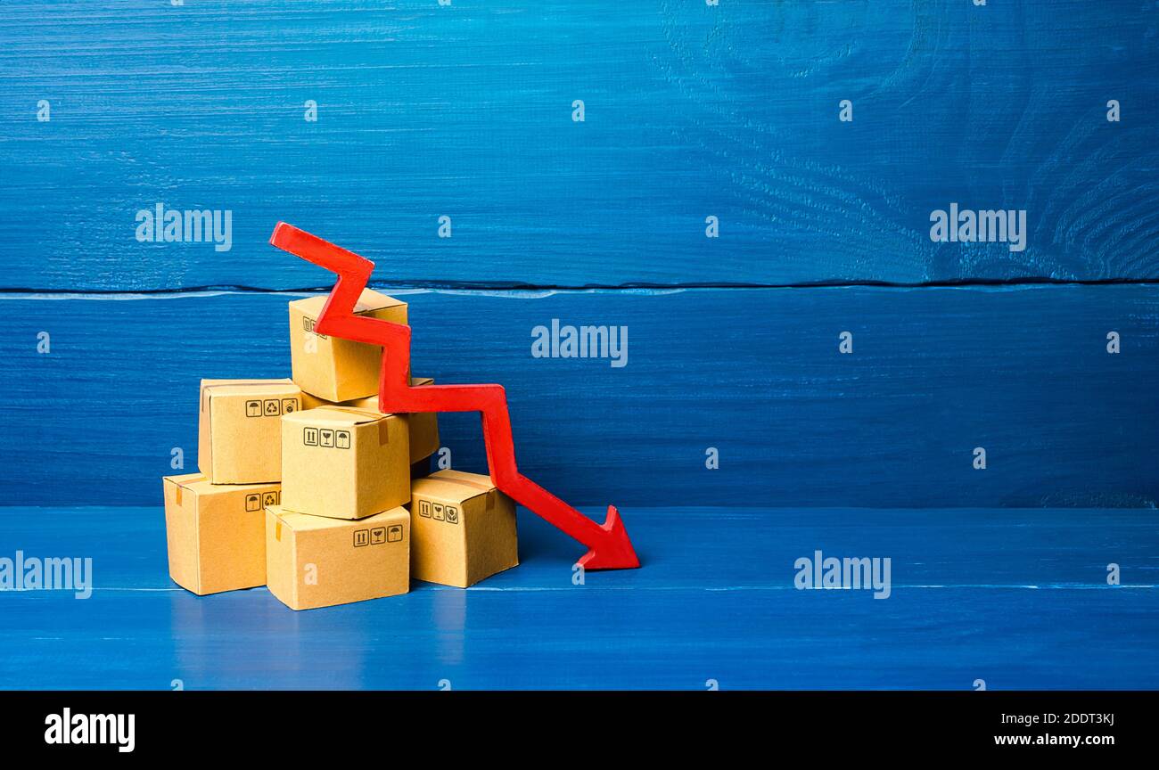 Cardboard boxes and red down arrow. Fall in sales and production of goods, low volume of delivery traffic and freight. Economic recession, skepticism Stock Photo