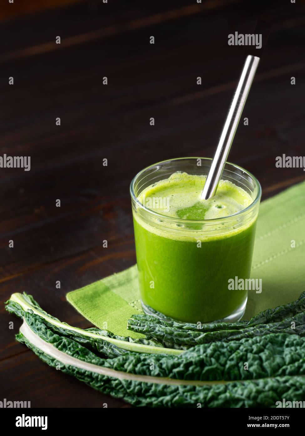 Glass of fresh organic vegetable juice with Dino kale on a wooden surface with a stainless steel drinking straw; copy space Stock Photo