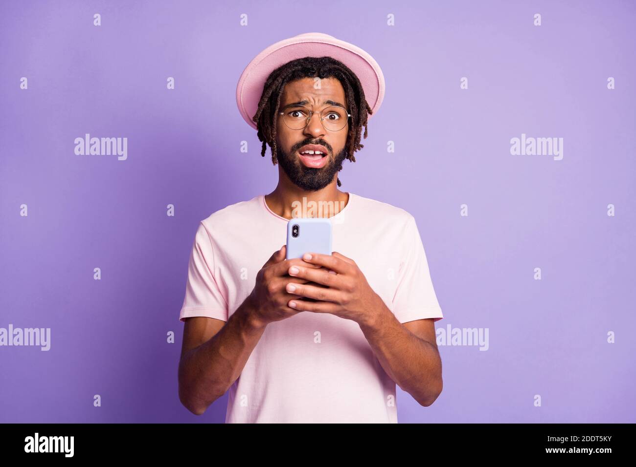 Photo portrait of unhappy man holding phone in two hands isolated on vivid violet colored background Stock Photo