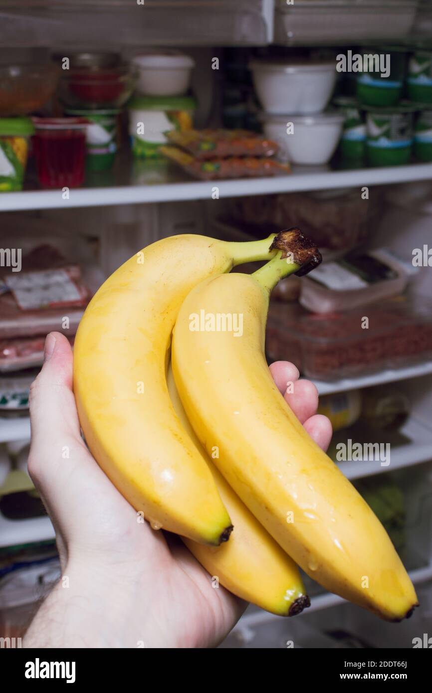 A hand puts fruit in the kitchen fridge. Closeup of a hand holding