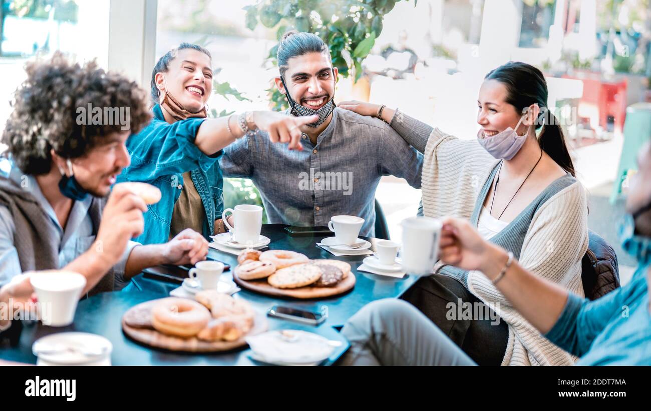 People having fun drinking and eating at coffeehouse - Young friends talking together at restaurant cafeteria - New normal lifestyle concept Stock Photo