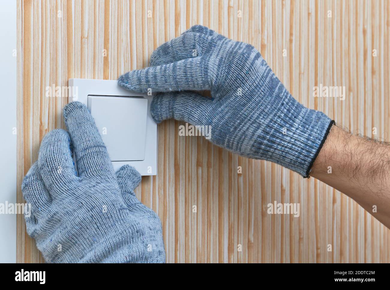 Installation of the wall switch in the room by an electrician, hands in close-up protective gloves Stock Photo