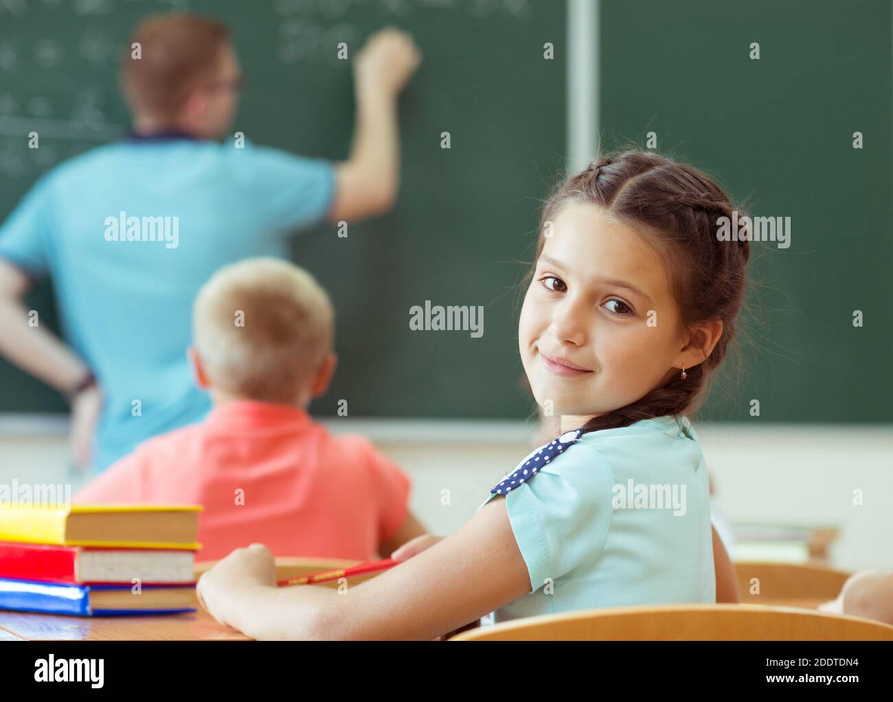 Cute smiling schoolgirl at school during lesson Stock Photo - Alamy