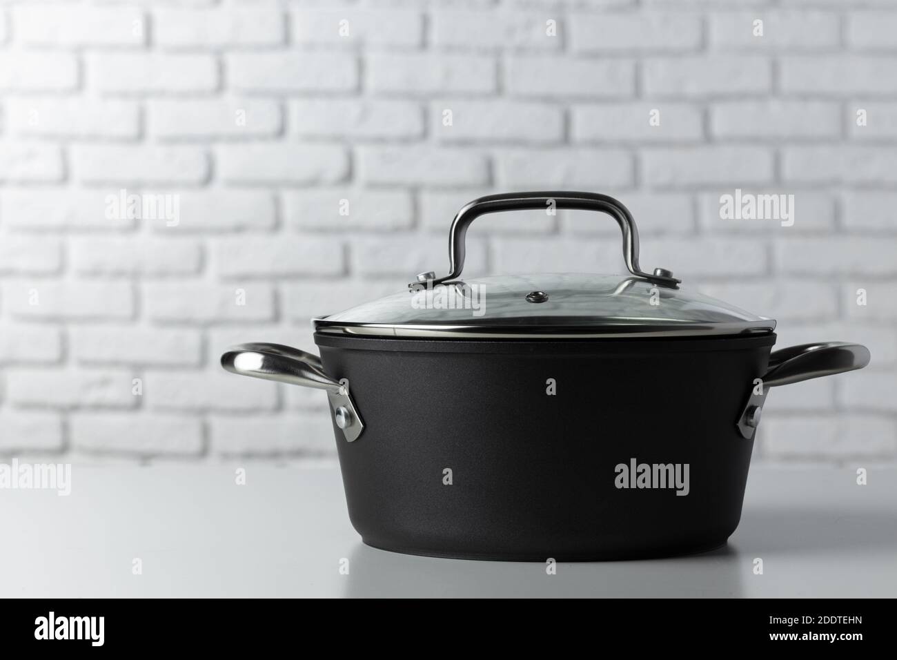 Cooking pot against white brick wall front view Stock Photo - Alamy