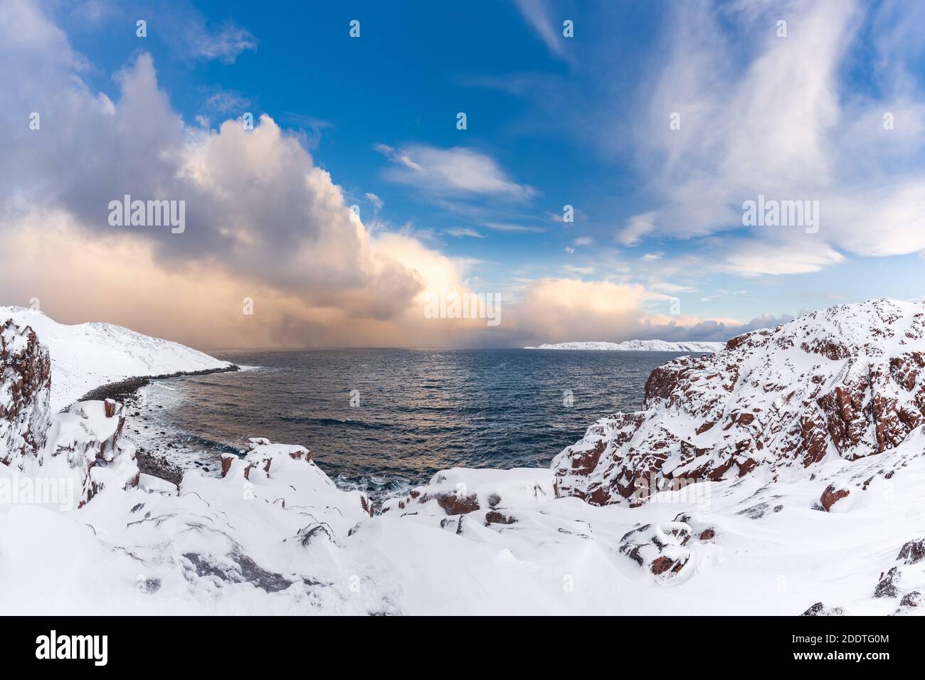 Winter panorama of Barents Sea gulf surrounded by snow covered rocky shores in the far North above the Arctic Circle in Russia's Kola peninsula Stock Photo