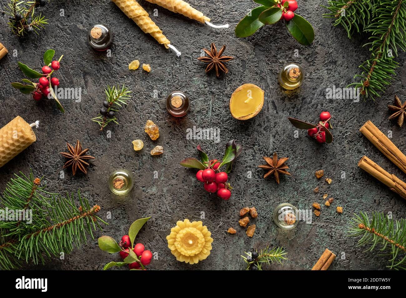 Christmas background with bottles of essential oil with frankincense, wintergreen, juniper, cinnamon and spruce on a dark background Stock Photo