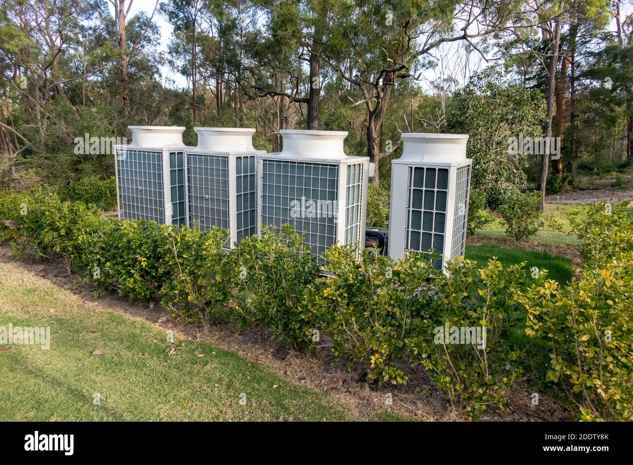 Air conditioner cooling towers outside in a garden surrounded by plants