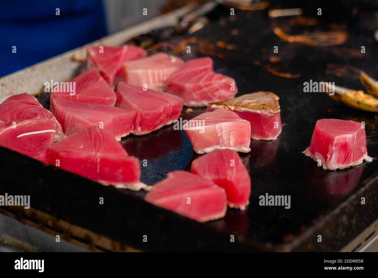 Close up: process of cooking fresh red tuna slices on grill - street food Stock Photo