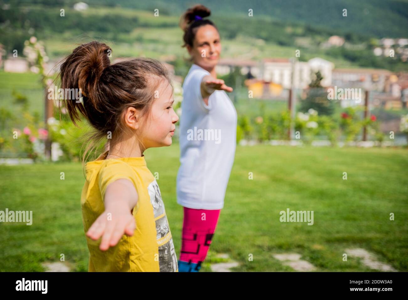 Mother and daughter doing yoga exercises outdoor - young woman doing fitness exercises in the park - Reach harmony Stock Photo