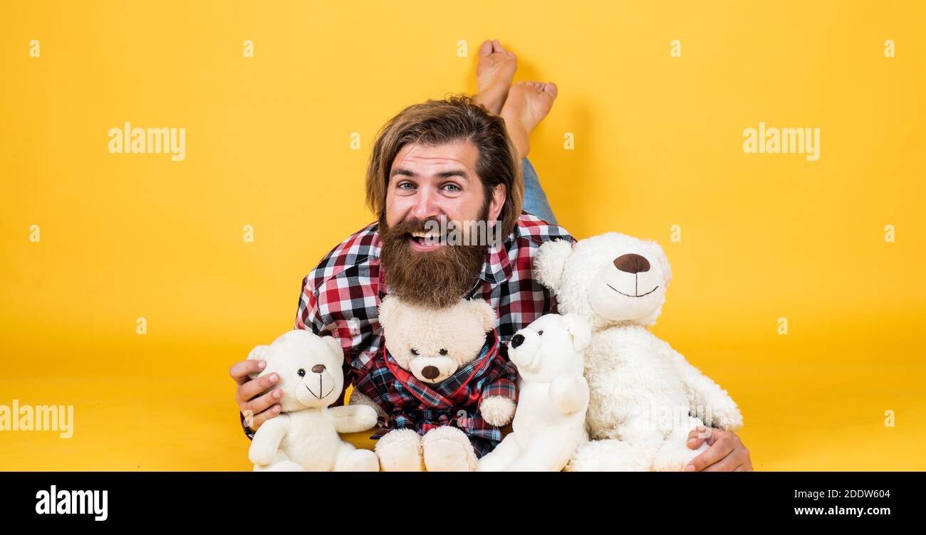 brutal bearded man wear checkered shirt having lush beard and moustache with teddy bear toy, happy birthday. Stock Photo