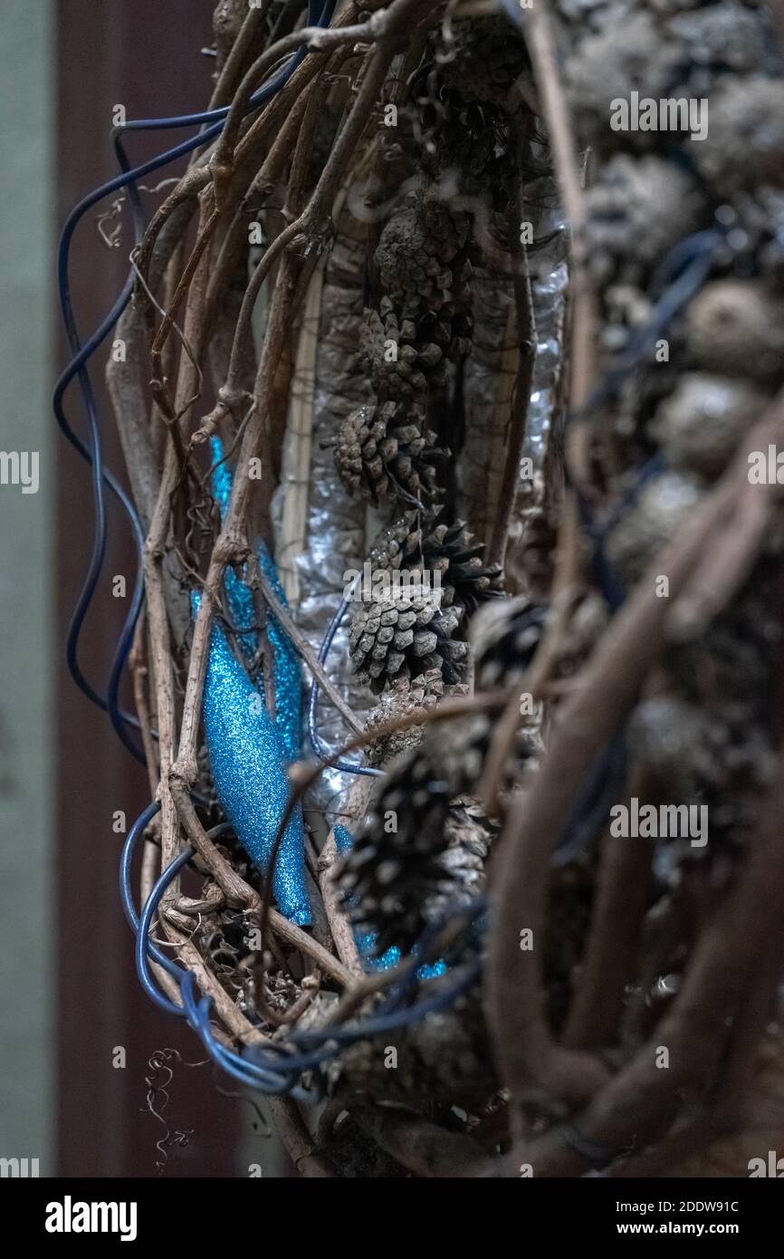 A detail of a Christmas composition.  Natural materials (wicker, tree twigs, pine cones) and artificial accessories (blue wire, blue plastic shiny toy Stock Photo