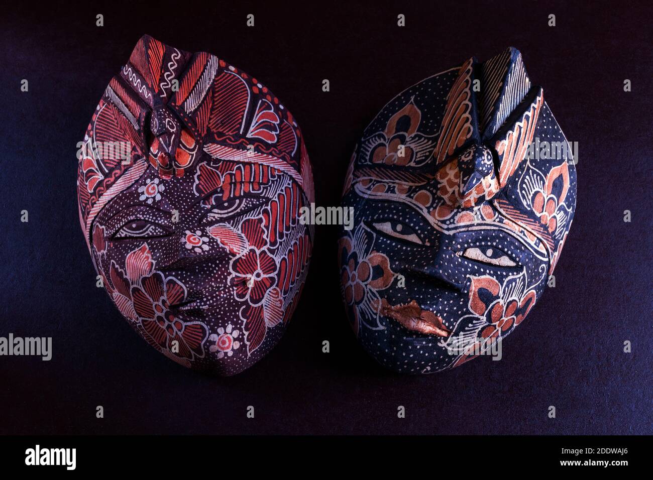 colored wooden african masks on dark red wine background for wall decoration. Stock Photo