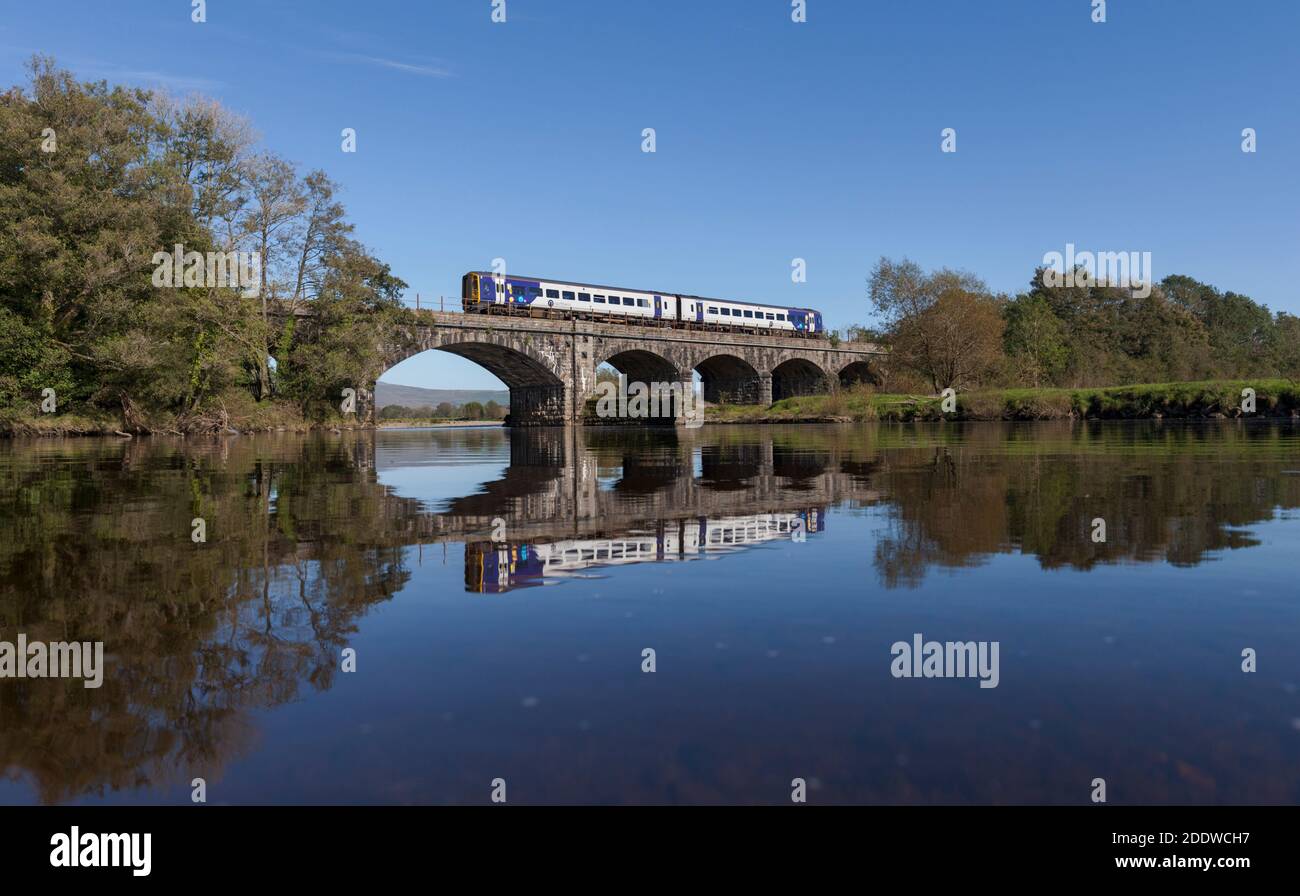 Northern Rail class 158 train crossing the river Lune viaduct at Arkholme on the ' little north western ' line in Lancashire, reflected in the river. Stock Photo