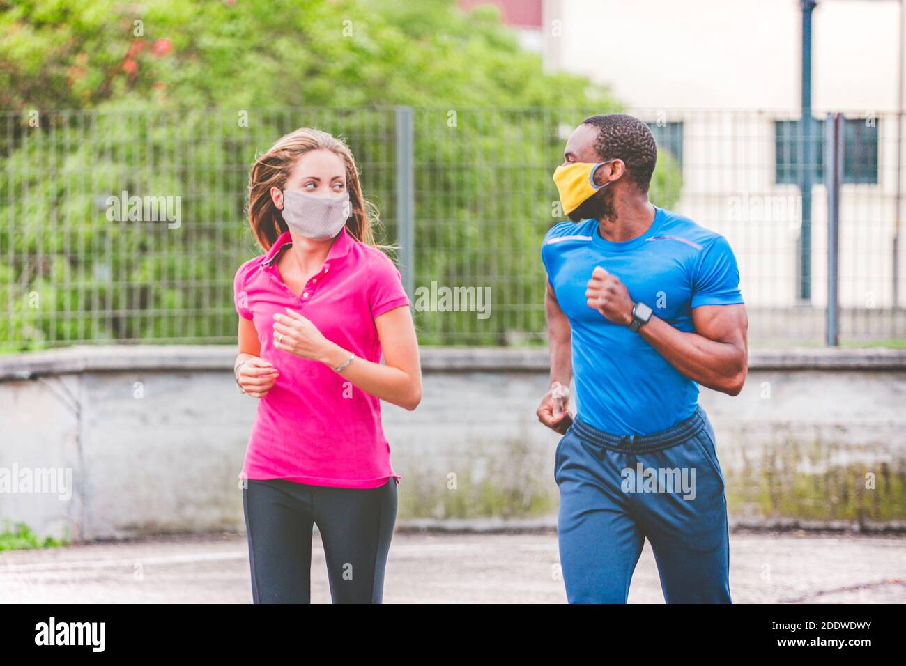 Young couple is jogging on the street wearing medical protective masks, out  to run. Afro american man and beautiful blonde girl in sportswear running  Stock Photo - Alamy
