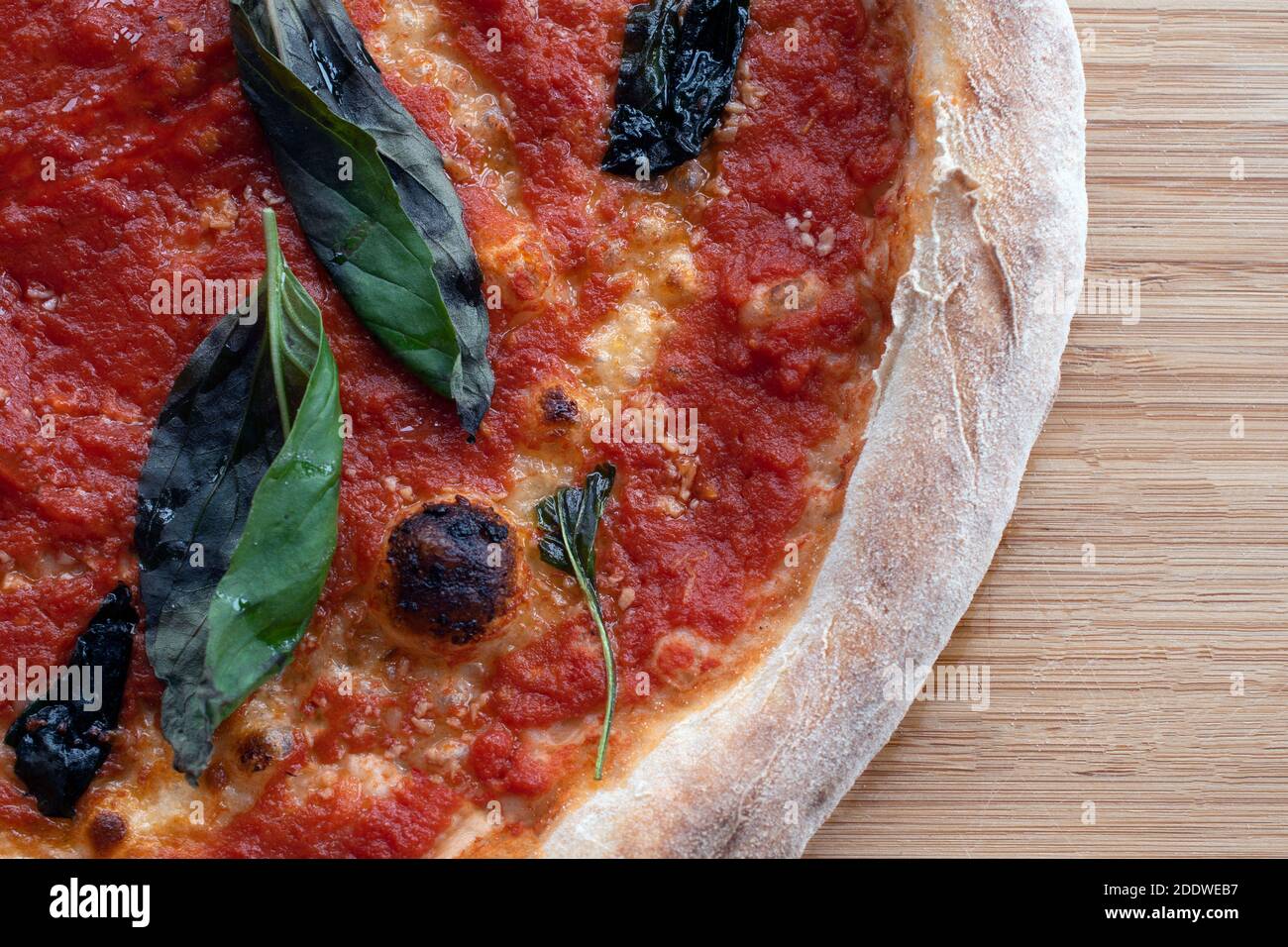 Overhead shot of a vegan cheese-less marinara pizza with basil leaves on a rustic wooden board Stock Photo