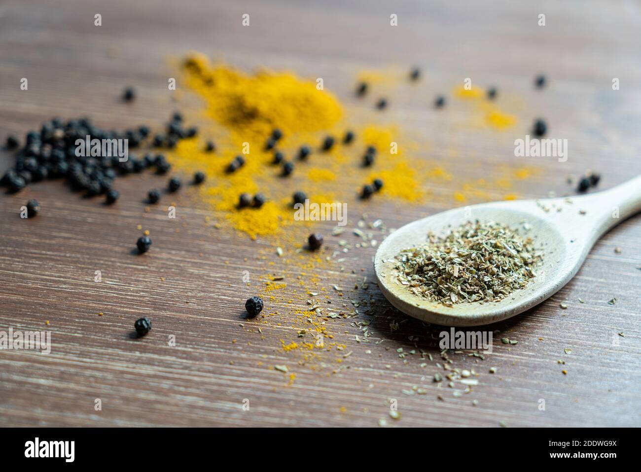 a wooden ladle with curry powder and pepper grain Stock Photo