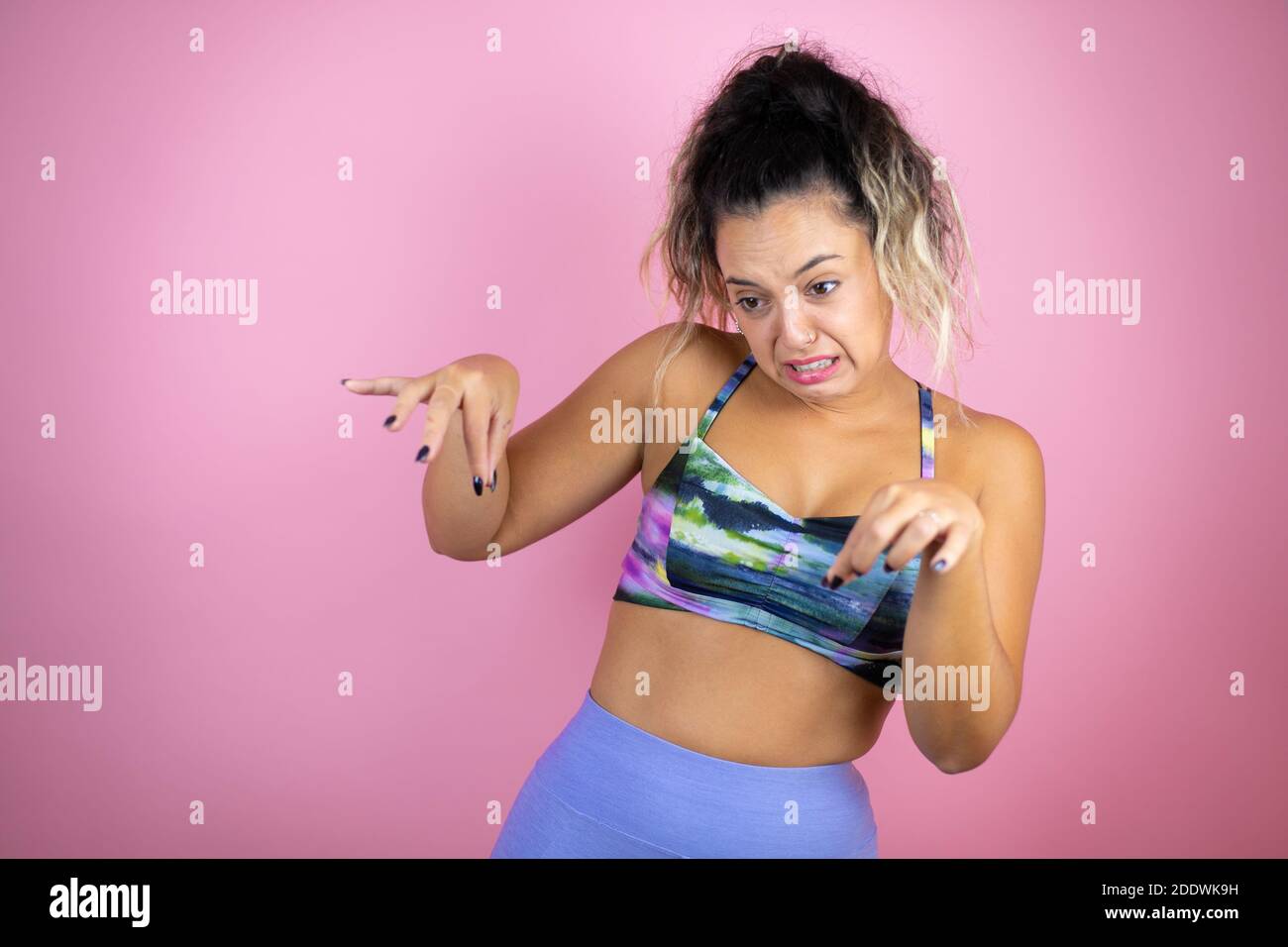 Young beautiful woman wearing sportswear over isolated pink background disgusted expression, displeased and fearful doing disgust face because aversio Stock Photo