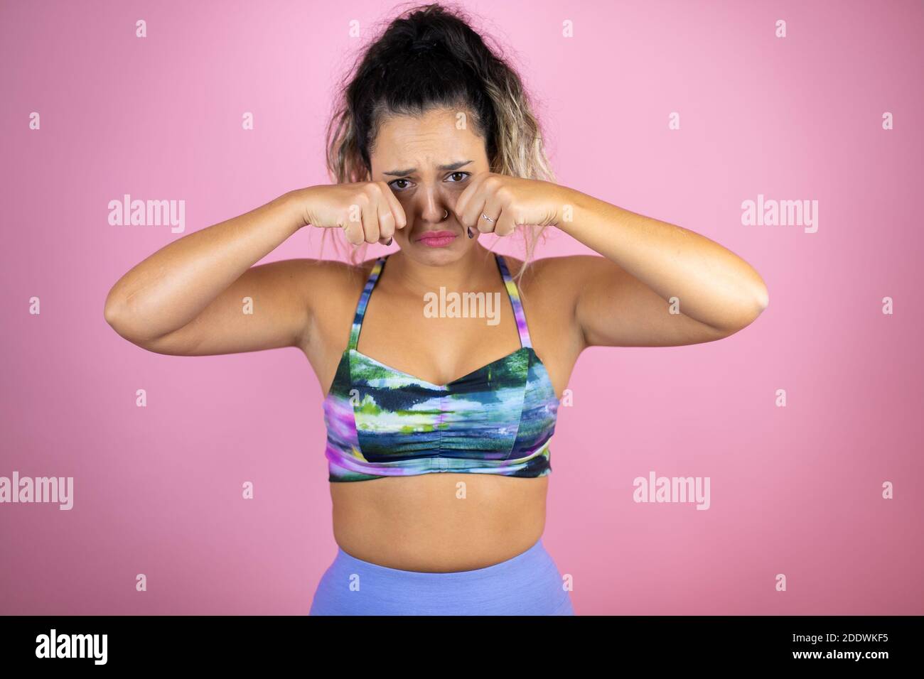 Young beautiful woman wearing sportswear over isolated pink background depressed and worry for distress, crying angry and afraid. Sad expression. Stock Photo