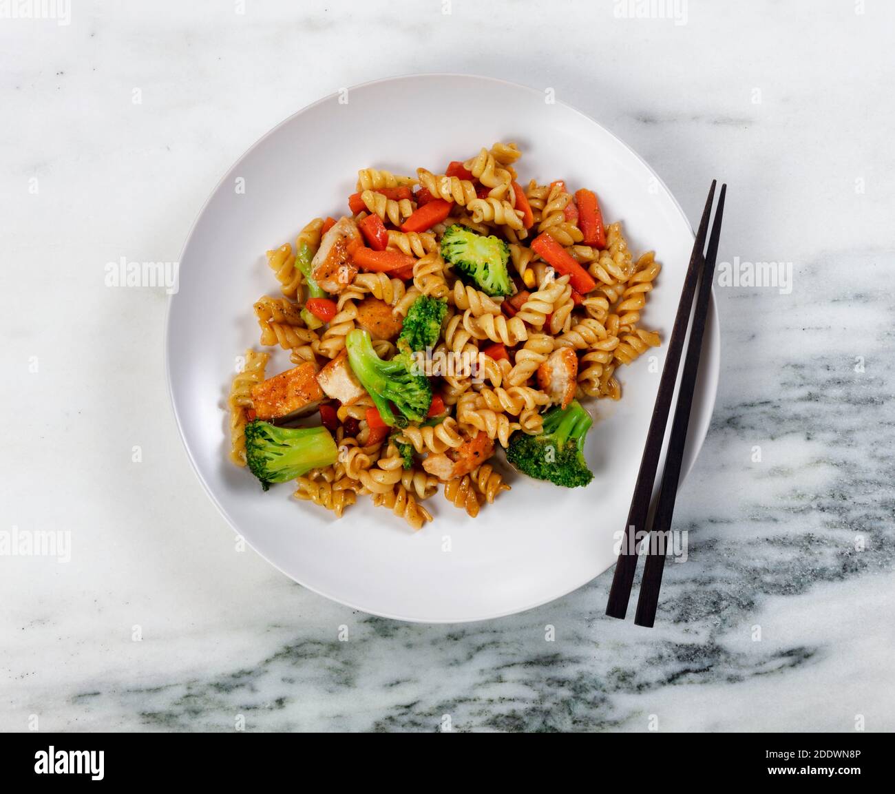 Close up of plate filled with healthy vegetables and noodles plus chopsticks as eating utensils Stock Photo