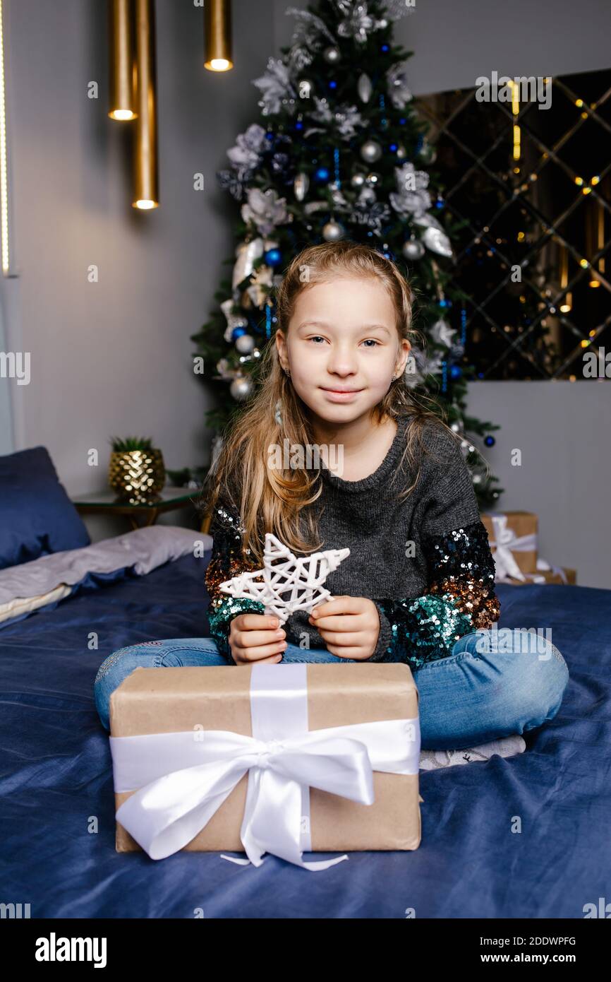 little girl smiling with gift box near the Christmas tree. Christmas ...