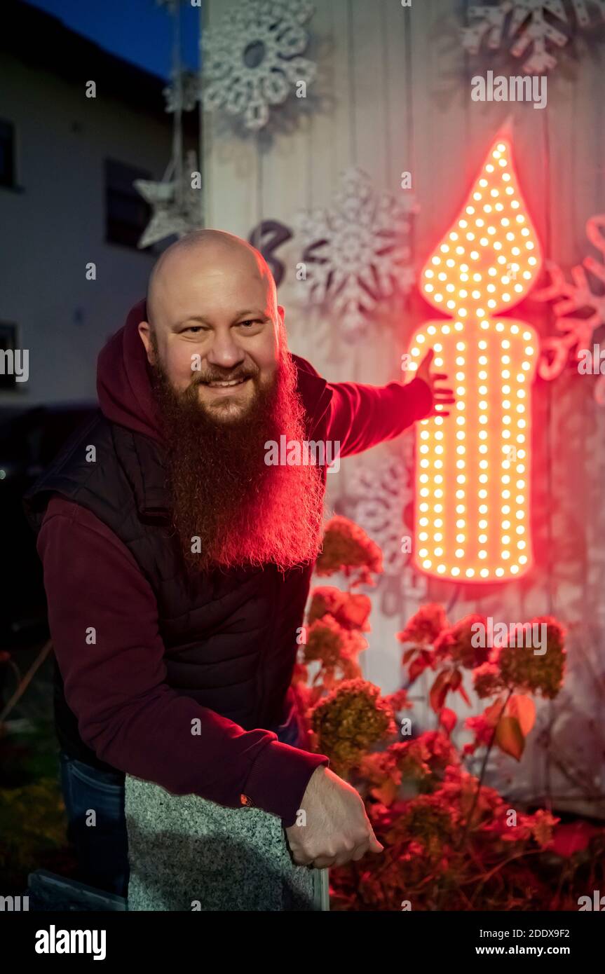Karlsruhe, Germany. 24th Nov, 2020. Thorsten Grüger points to a red shining LED candle at his house, which he has placed there. In order to avoid crowds of people accumulating during the Corona pandemic, he does without the otherwise lavish lighting at his Christmas house. With the candle he wants to remind and remind those who are affected by the virus. (to dpa: 'Christmas houses are shining again - ray of hope in the Corona crisis') Credit: Uli Deck/dpa/Alamy Live News Stock Photo