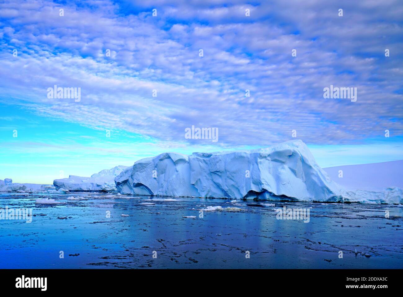 The blue sky shows radial clouds, icebergs and the deep blue sea