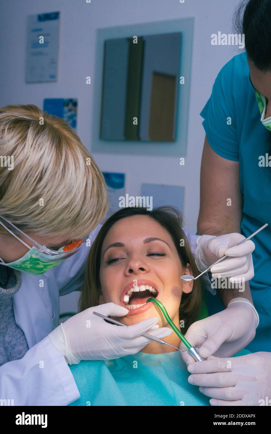 Professional male and female dentists examining woman's teeth in dental