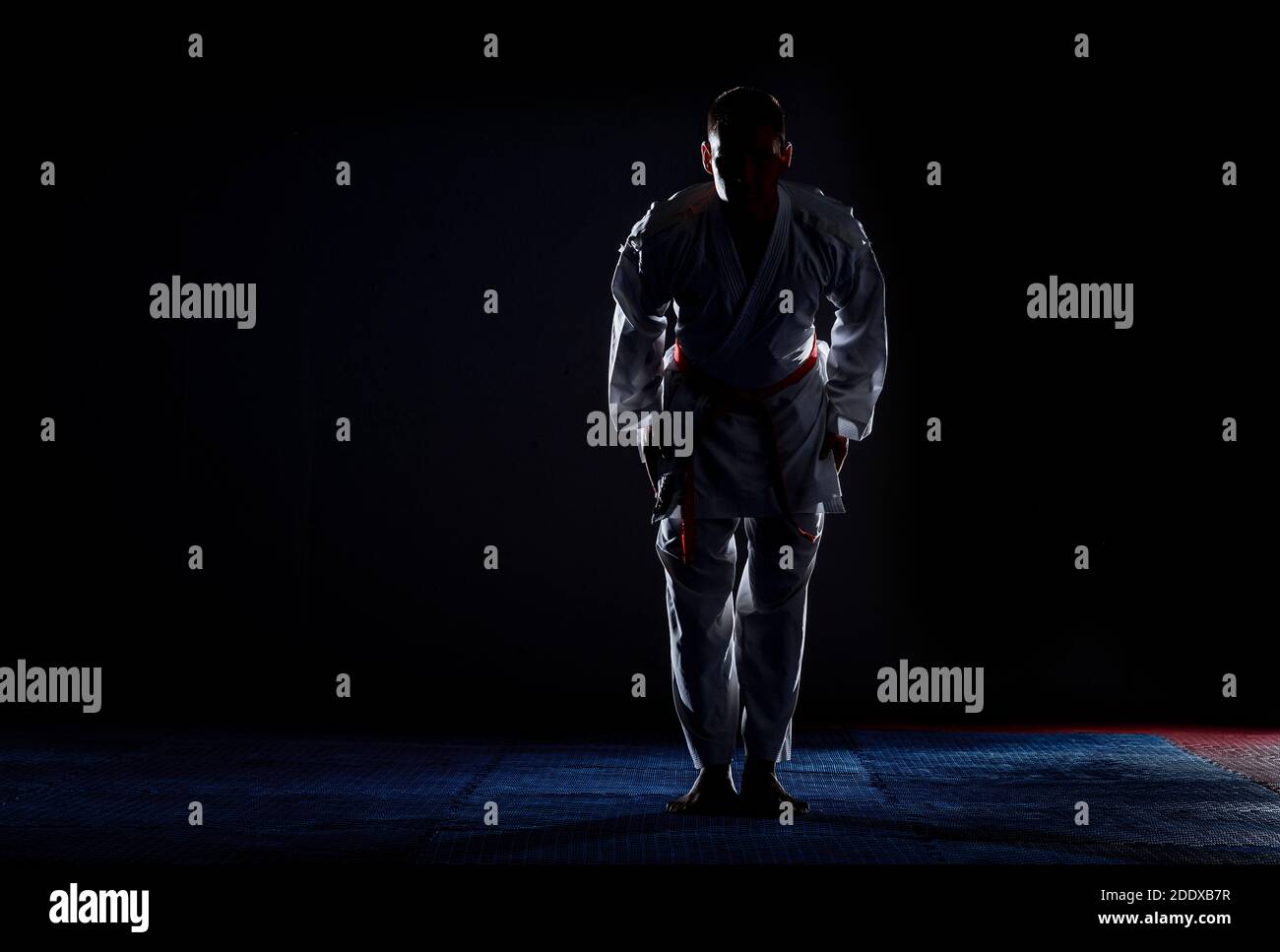 Karate man posing on a dark background wearing white kimono Stock Photo