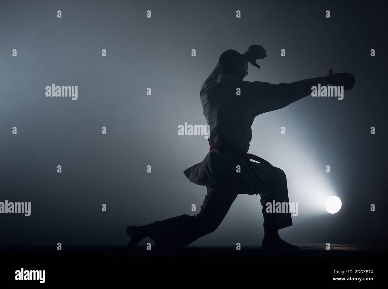 Karate man posing on a dark background wearing white kimono Stock Photo