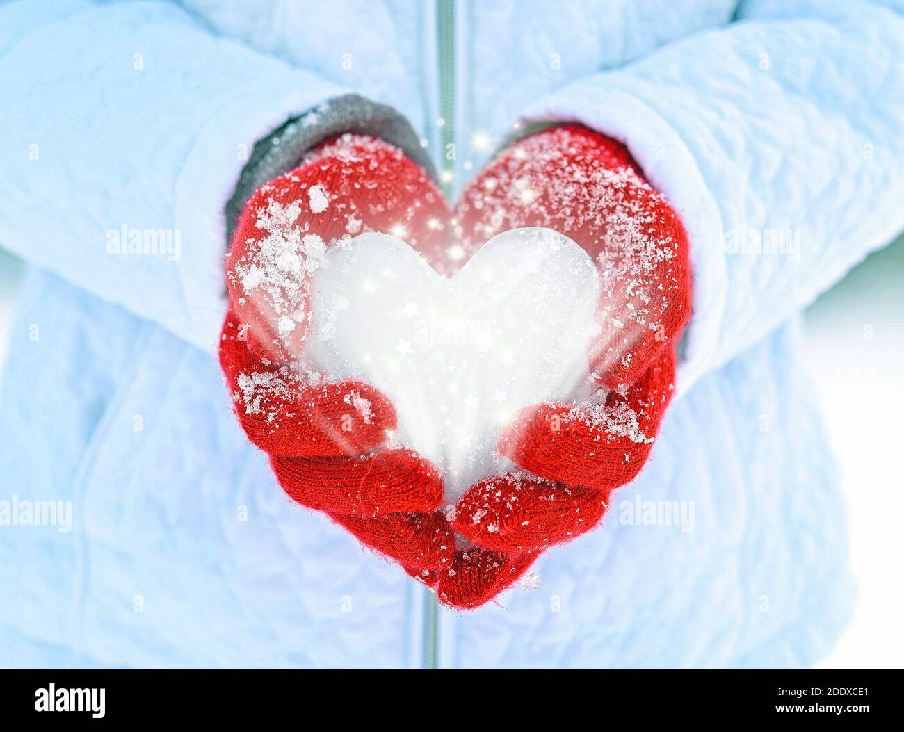 close up of red gloves holding ice heart with glowing sparkles and stars Stock Photo