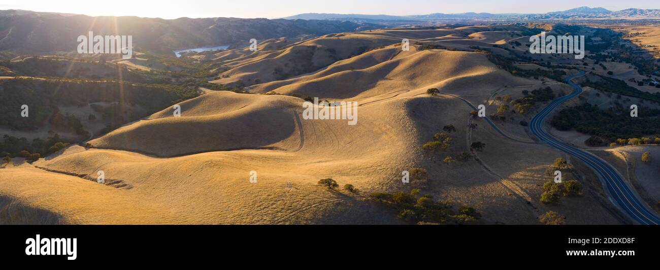 Golden sunlight shines on the rolling hills in Northern California. These beautiful, eroded hills turn green once winter brings seasonal rain. Stock Photo