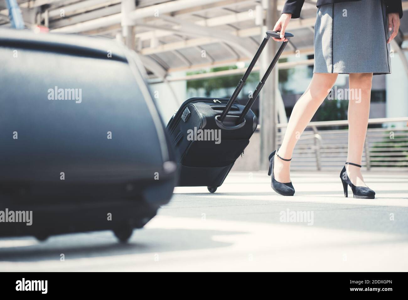 Businesswoman (lower part) walking and pulling luggage - business traveling concept Stock Photo