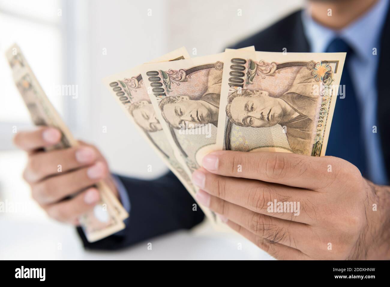 Businessman counting money calculating conversion rate of Japanese yen  banknote currency in his hands Stock Photo - Alamy