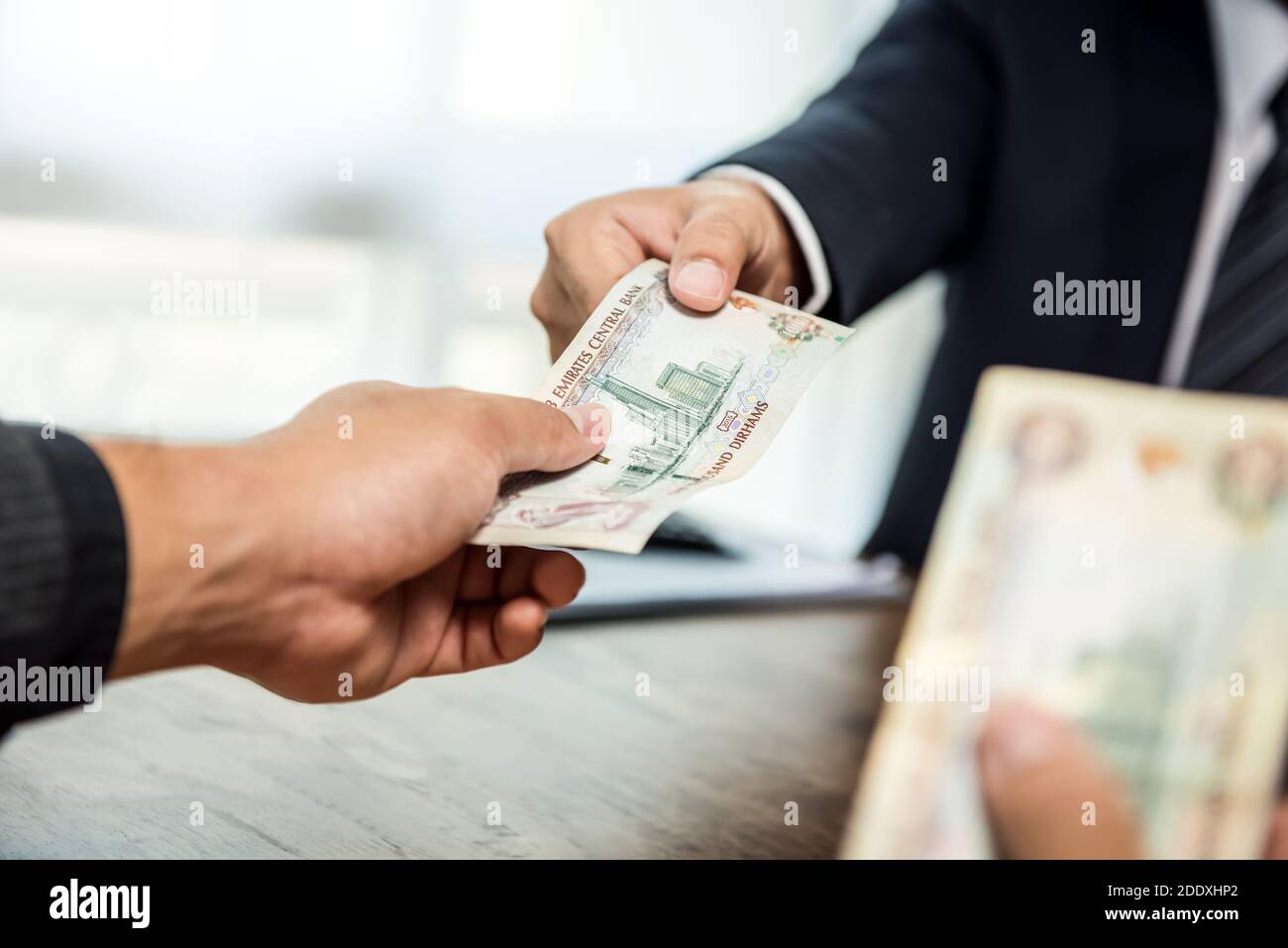 Businessman giving money, United Arab Emirates dirham currency, to his partner Stock Photo