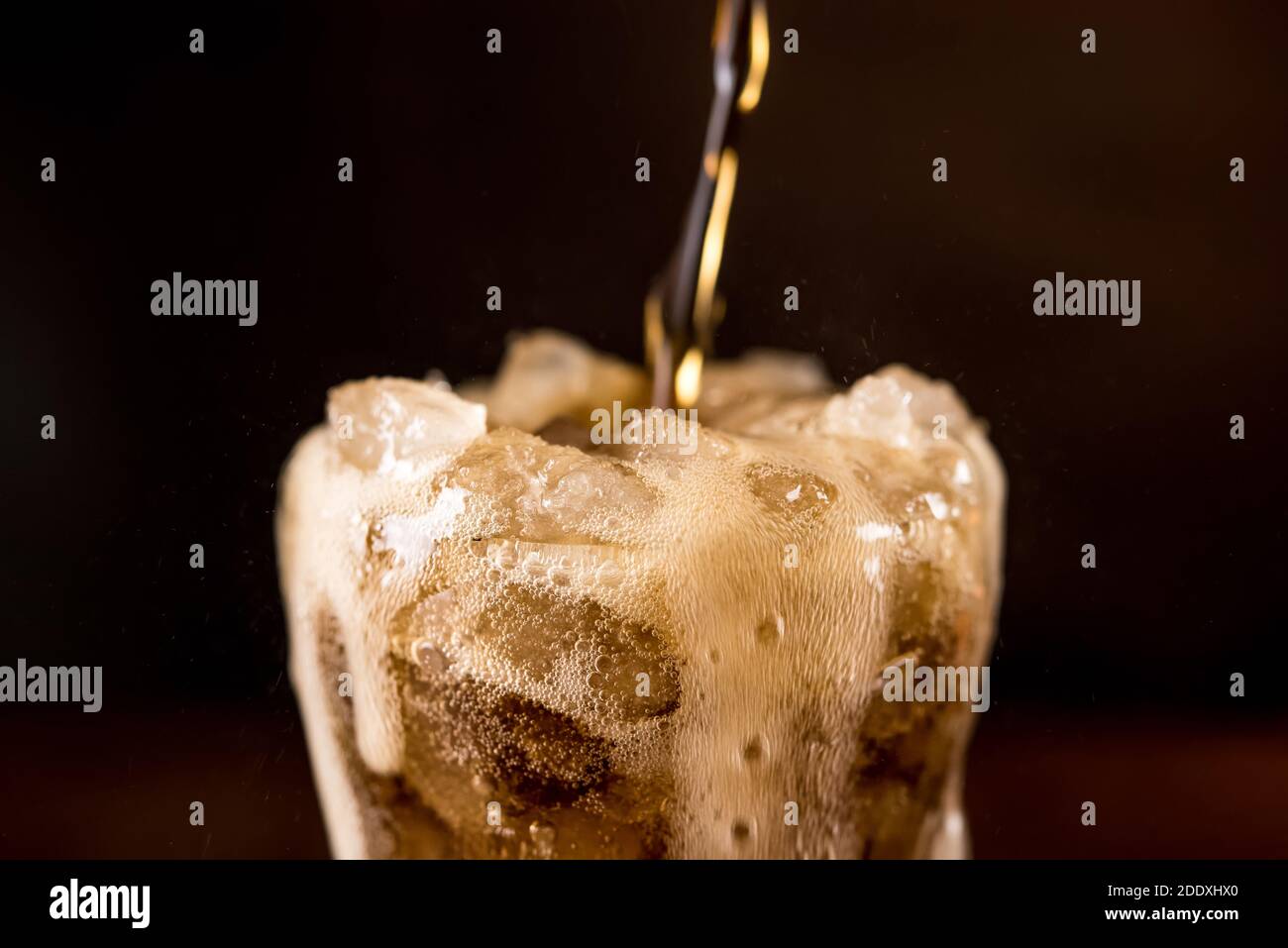 Close up of sparkling carbonated cold fresh cola drink being poured into the glass with overflowed foam bubble on top Stock Photo