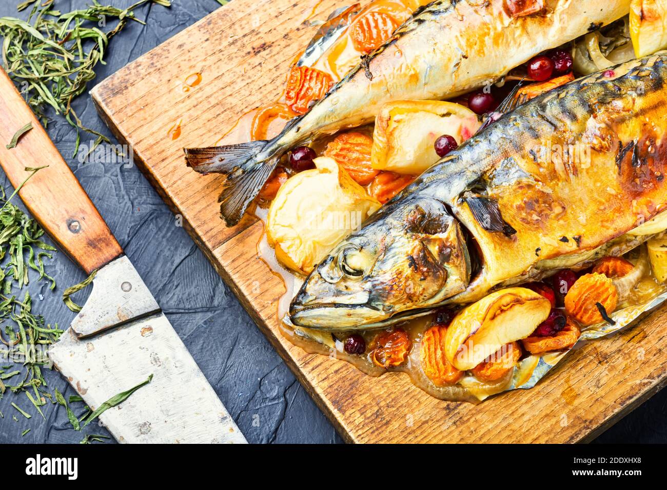 Delicious mackerel fish baked with apples,served on a kitchen board. Stock Photo