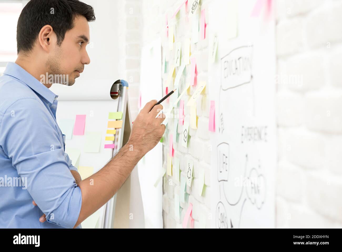 Asian male teacher standing and searching for infoamtion at the board in classroom Stock Photo