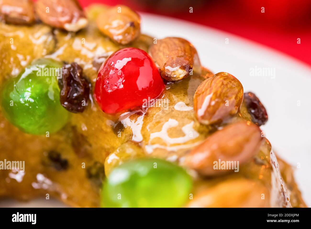 Close up of glazed colorful Christmas fruitcake topped with almonds and glace cherries Stock Photo