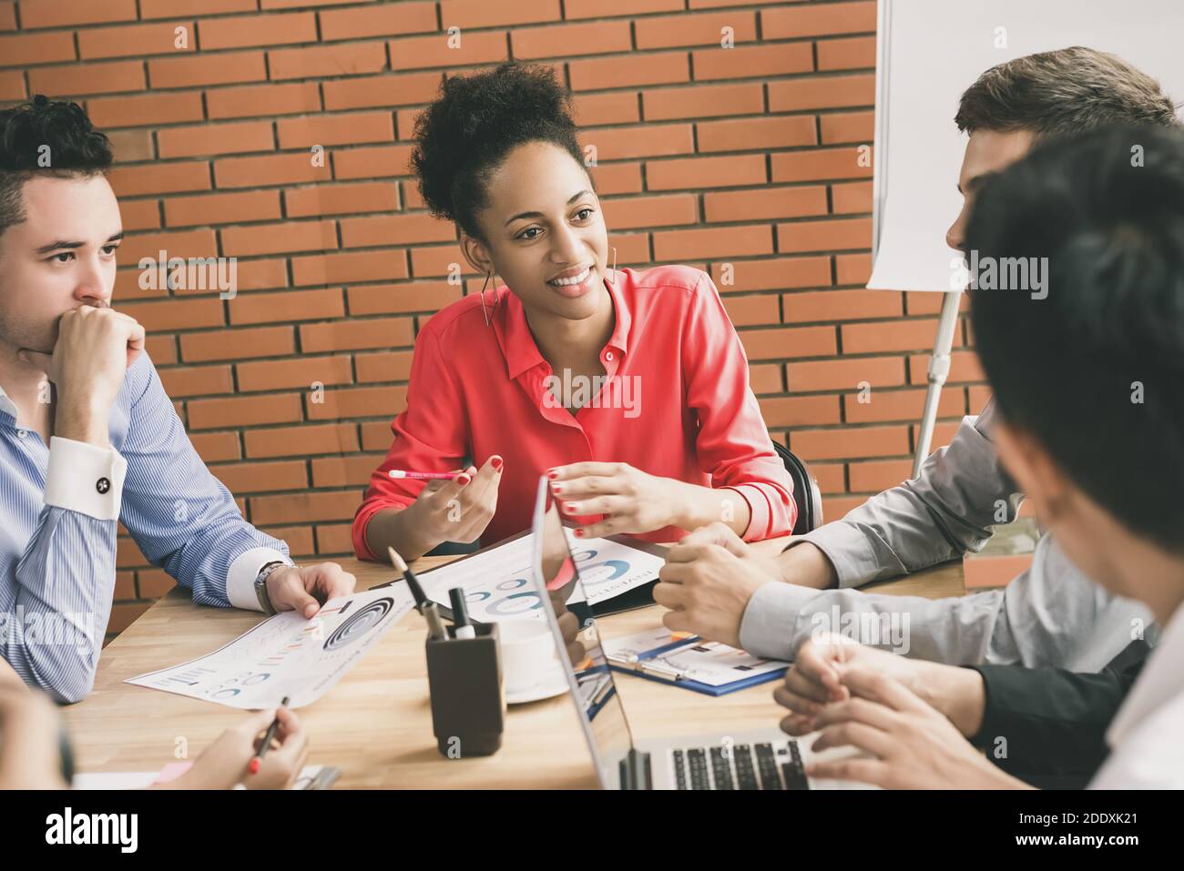 Young casual interracial business people paying attention to their colleague in group discussion at meeting room Stock Photo