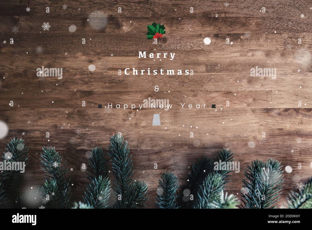 Merry Christmas and Happy New Year text on wood table background with snow and green pine tree leaf decorations, top view Stock Photo