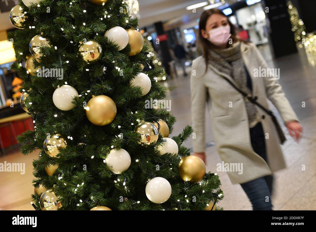 Topic picture prisoners in the coronavirus pandemic on November 26th, 2020. A young woman with face mask, mask walks past a Weihaftertsbaum in a mall, shopping center. Pandemic, lockdown, shutdown, incidence value. MODEL RELEASED! | usage worldwide Stock Photo