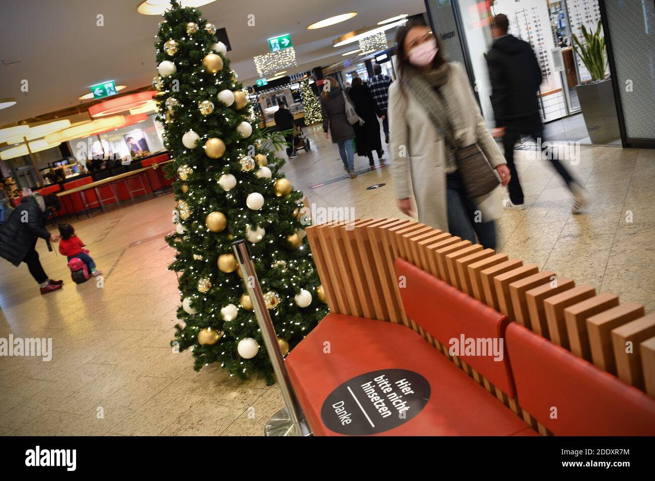 Topic picture prisoners in the coronavirus pandemic on November 26th, 2020. A young woman with face mask, mask walks past a Weihaftertsbaum in a mall, shopping center. Pandemic, lockdown, shutdown, incidence value. MODEL RELEASED! | usage worldwide Stock Photo