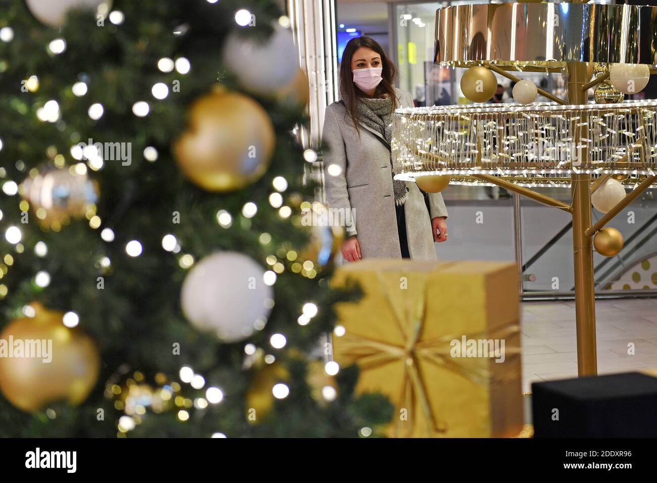 Topic picture prisoners in the coronavirus pandemic on November 26th, 2020. A young woman with face mask, mask stands behind a Weihaftertsbaum in a mall, shopping center. Pandemic, lockdown, shutdown, incidence value. MODEL RELEASED! | usage worldwide Stock Photo