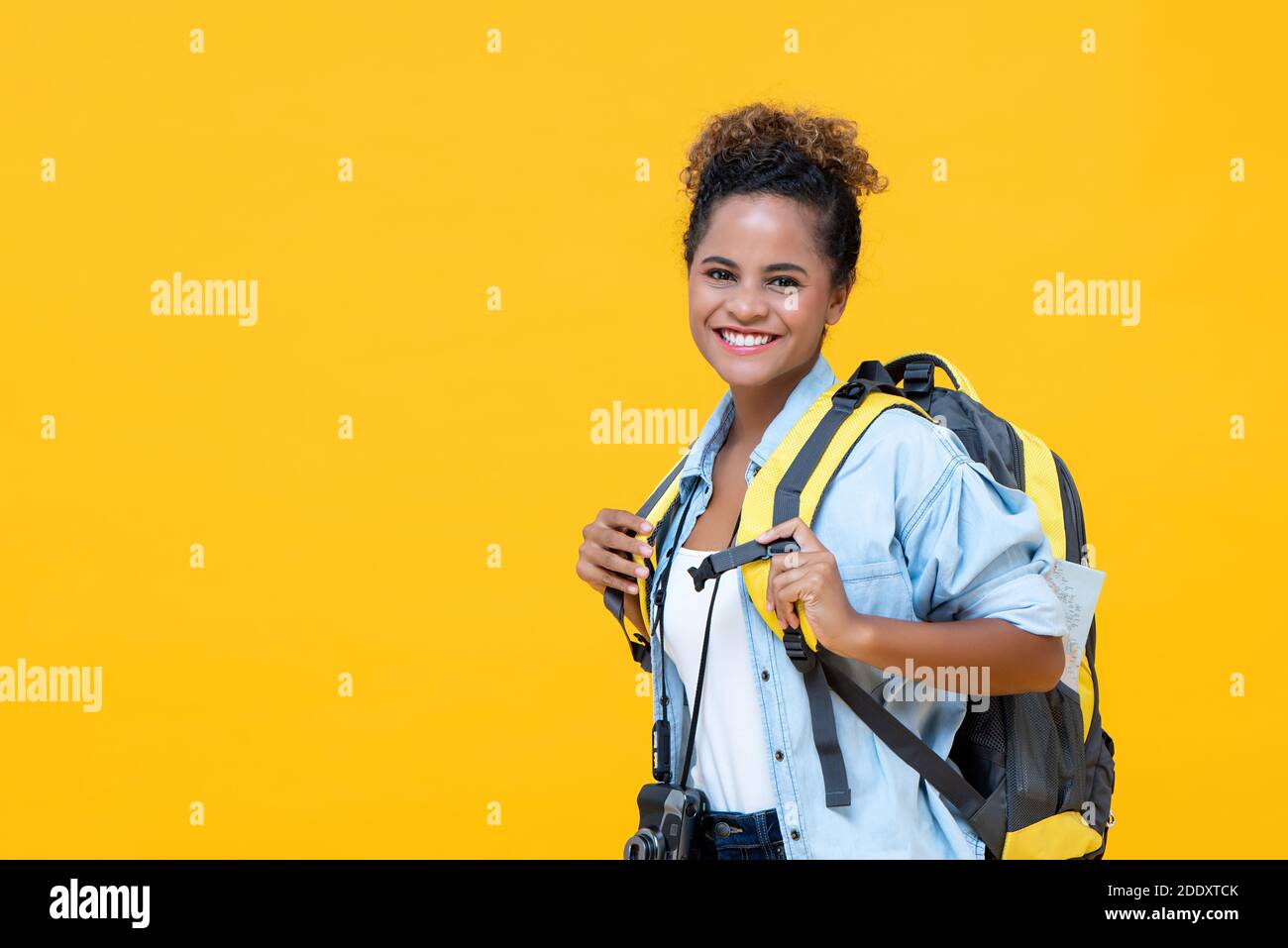 Beautiful young African American woman tourist backpacker solo traveling isolated on yellow studio background with copy space Stock Photo