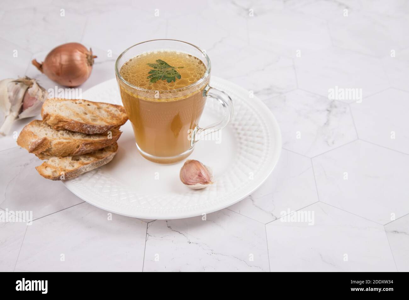 Hearty meat broth in a glass Cup on a napkin with crackers on a light