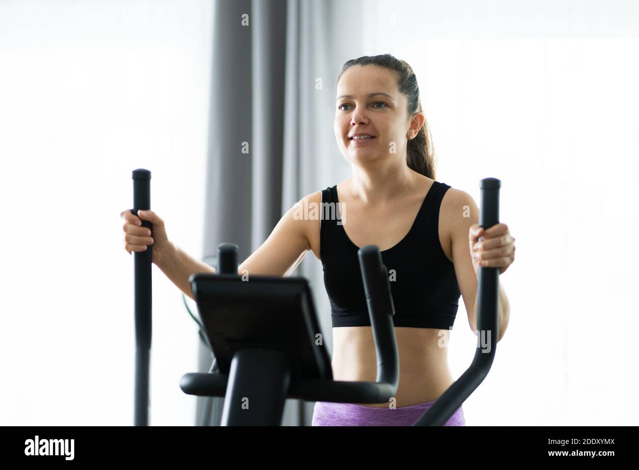 Woman Training On Elliptical Trainer At Home Stock Photo