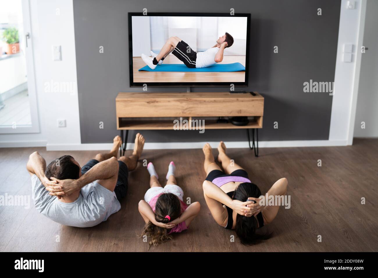 Family Family Doing Fitness Exercise While Watching TV Stock Photo